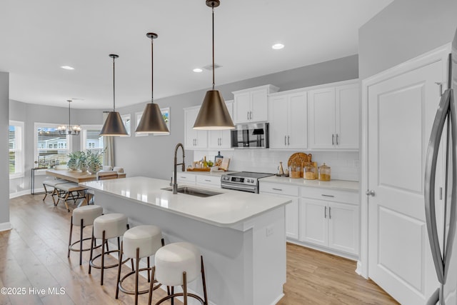 kitchen featuring a breakfast bar, a sink, appliances with stainless steel finishes, decorative backsplash, and light wood finished floors