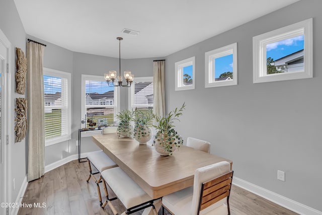 dining room featuring light wood-type flooring, visible vents, baseboards, and an inviting chandelier