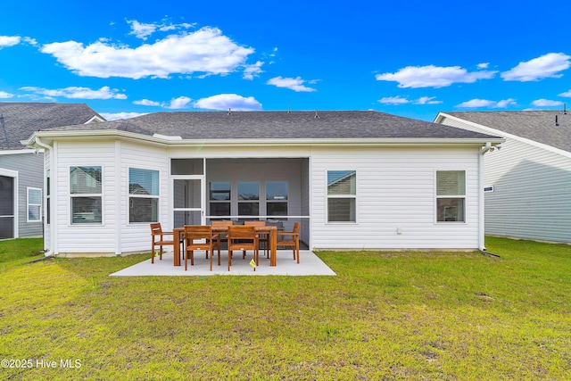 back of property featuring roof with shingles, a patio, and a lawn