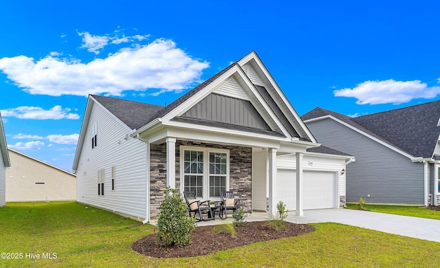 view of front of property featuring driveway, a garage, stone siding, a front lawn, and board and batten siding