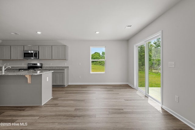 6986 Seaside Palms Pl SW, Sunset Beach, NC 28468 - kitchen with gray cabinetry, appliances with stainless steel finishes, plenty of natural light, a kitchen bar, and recessed lighting