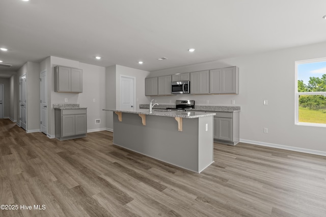 6986 Seaside Palms Pl SW, Sunset Beach, NC 28468 - kitchen with gray cabinets, stainless steel appliances, light wood-style flooring, a kitchen island with sink, and recessed lighting