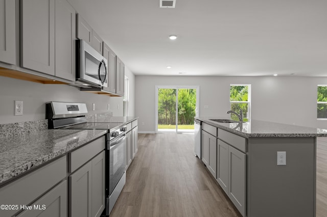 6986 Seaside Palms Pl SW, Sunset Beach, NC 28468 - kitchen with stainless steel appliances, gray cabinets, light wood-style floors, a center island with sink, and recessed lighting