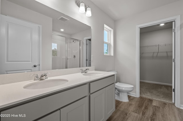 6986 Seaside Palms Pl SW, Sunset Beach, NC 28468 - bathroom featuring a stall shower, double vanity, a spacious closet, and wood finished floors