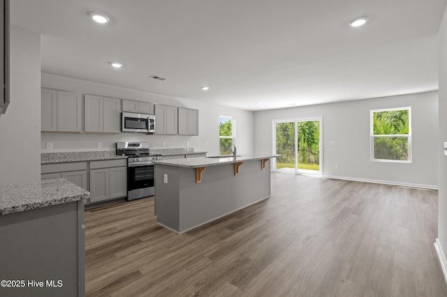 6986 Seaside Palms Pl SW, Sunset Beach, NC 28468 - kitchen featuring appliances with stainless steel finishes, gray cabinets, a breakfast bar area, light wood-style flooring, and recessed lighting