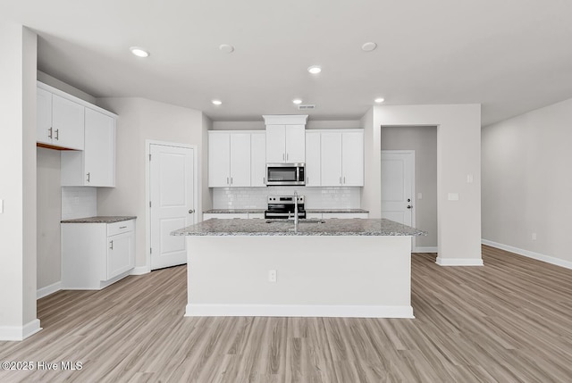 kitchen featuring sink, stainless steel appliances, an island with sink, and white cabinets