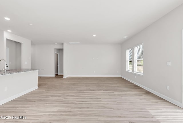 unfurnished living room with sink and light wood-type flooring