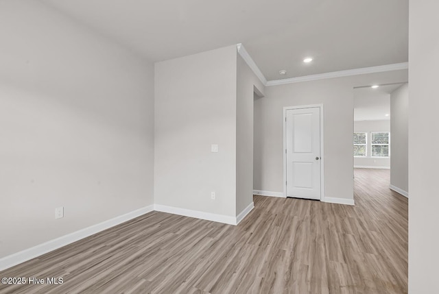 spare room with crown molding and light wood-type flooring