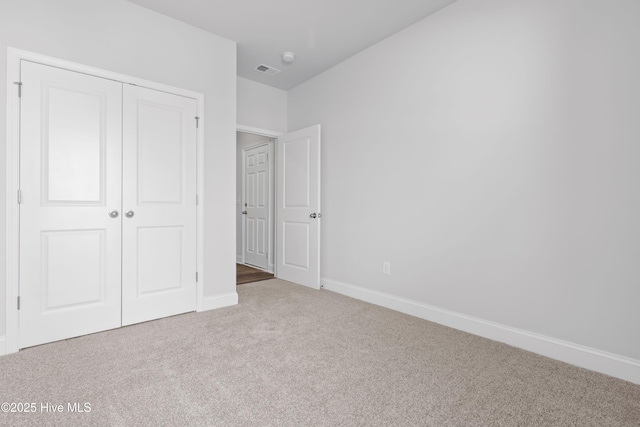 unfurnished bedroom with a closet, carpet, visible vents, and baseboards