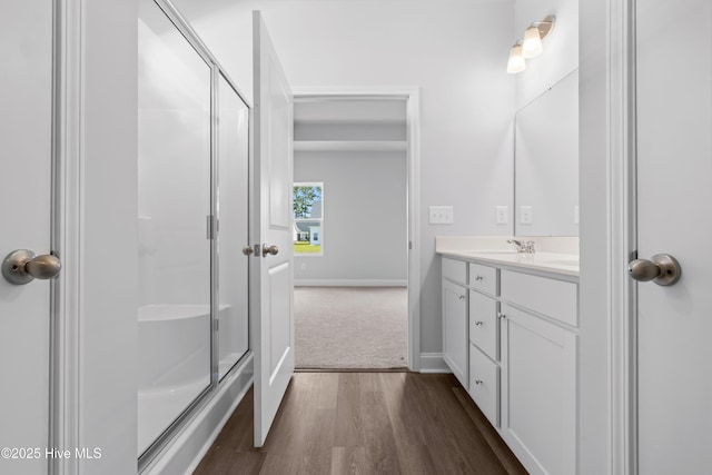 bathroom featuring a stall shower, vanity, baseboards, and wood finished floors