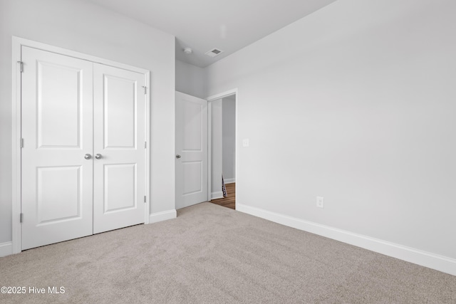 unfurnished bedroom with baseboards, a closet, visible vents, and carpet flooring