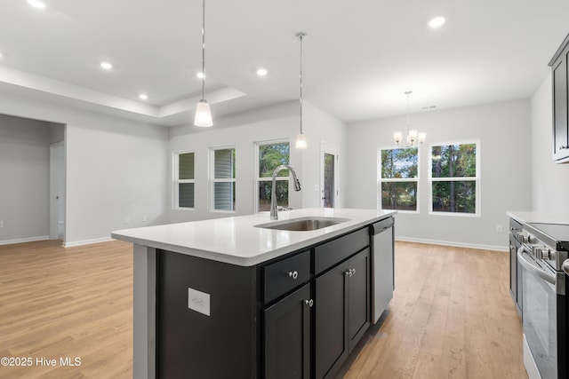 kitchen with a sink, light wood-style floors, light countertops, appliances with stainless steel finishes, and a raised ceiling