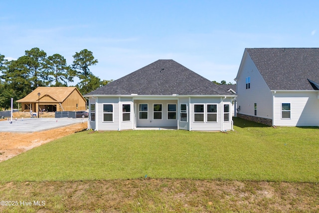 back of house with a shingled roof and a lawn