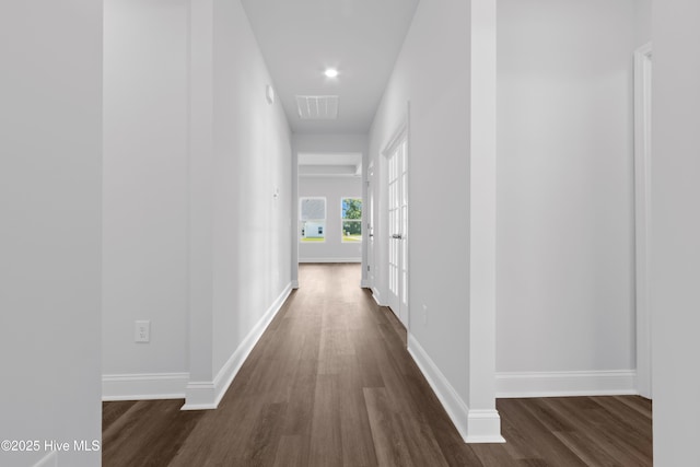 corridor featuring dark wood-style floors, visible vents, and baseboards