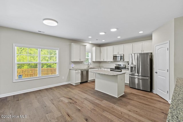 kitchen featuring a sink, appliances with stainless steel finishes, wood finished floors, and white cabinets