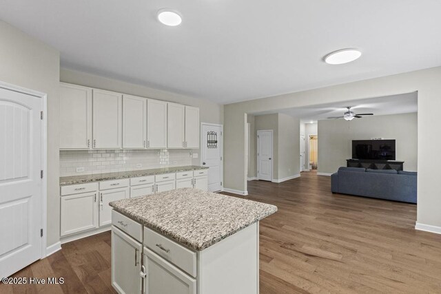 311 Mckenzie Pl, Sneads Ferry, NC 28460 - kitchen with wood finished floors, white cabinets, a center island, open floor plan, and decorative backsplash