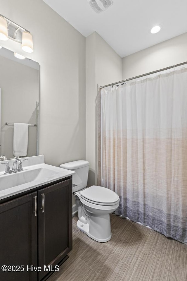 bathroom with toilet, visible vents, and vanity