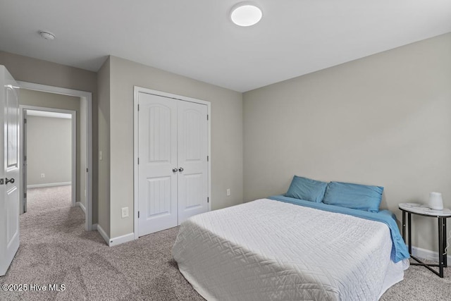 bedroom with baseboards, a closet, and light colored carpet