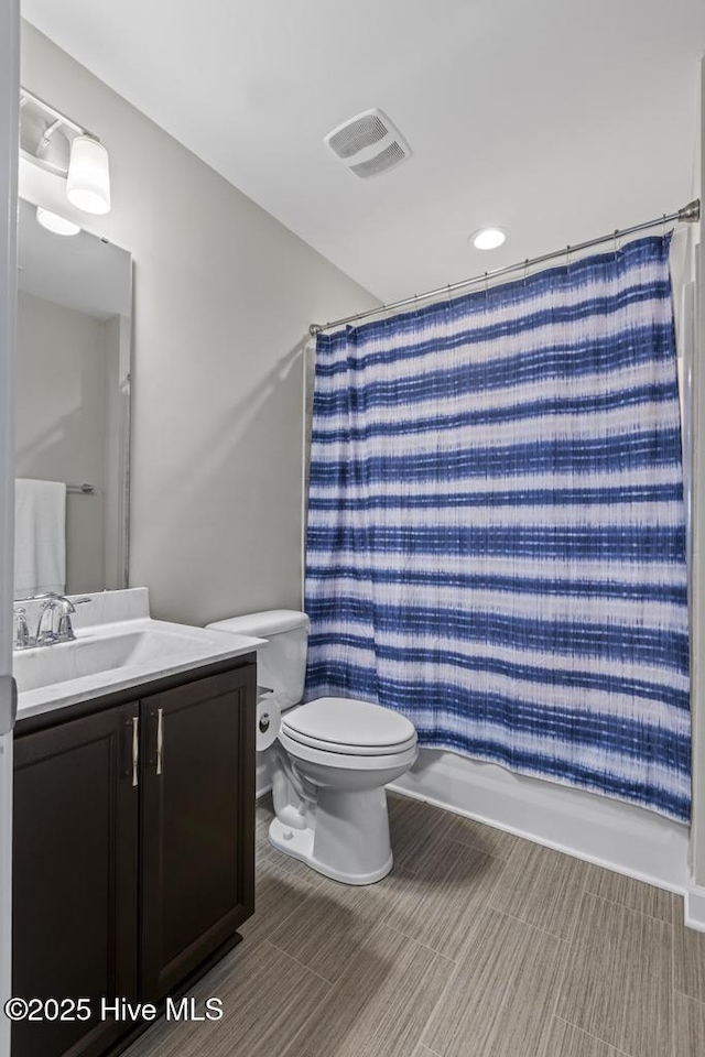 full bathroom with visible vents, a shower with shower curtain, toilet, and vanity