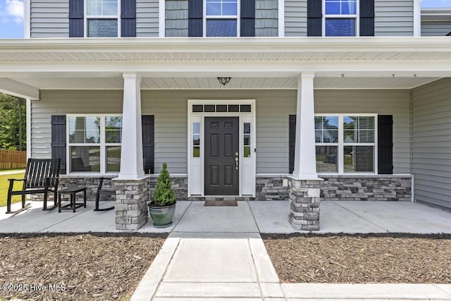 entrance to property featuring a porch and stone siding