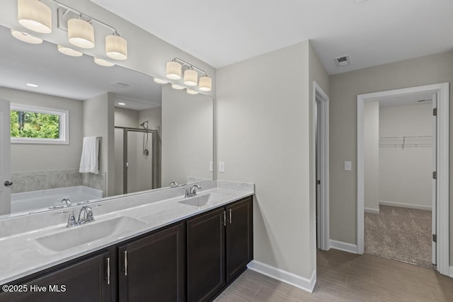 bathroom featuring double vanity, visible vents, a shower stall, and a sink