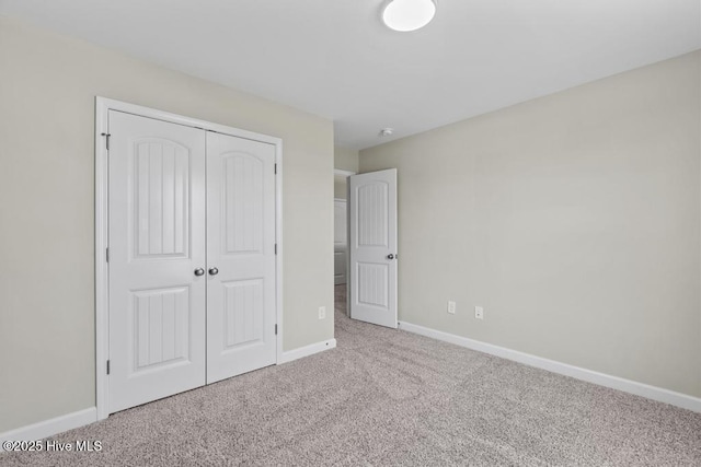 unfurnished bedroom with a closet, baseboards, and carpet flooring