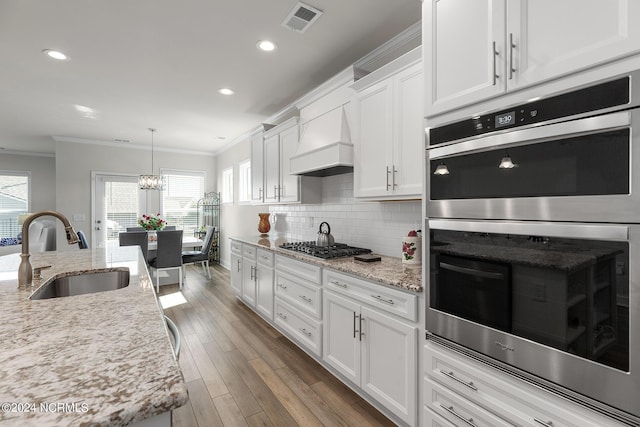 kitchen featuring sink, crown molding, stainless steel appliances, custom range hood, and white cabinets