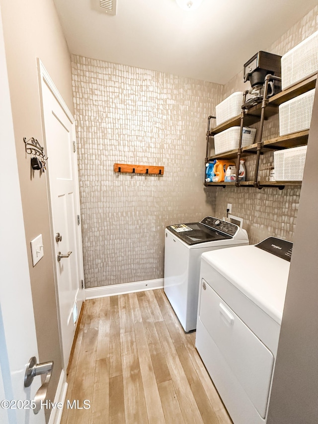 washroom with light hardwood / wood-style flooring and washing machine and dryer