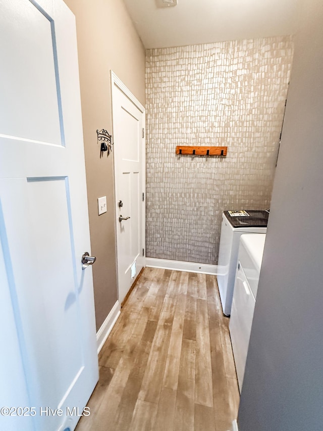 laundry room featuring light hardwood / wood-style floors, washing machine and dryer, and tile walls