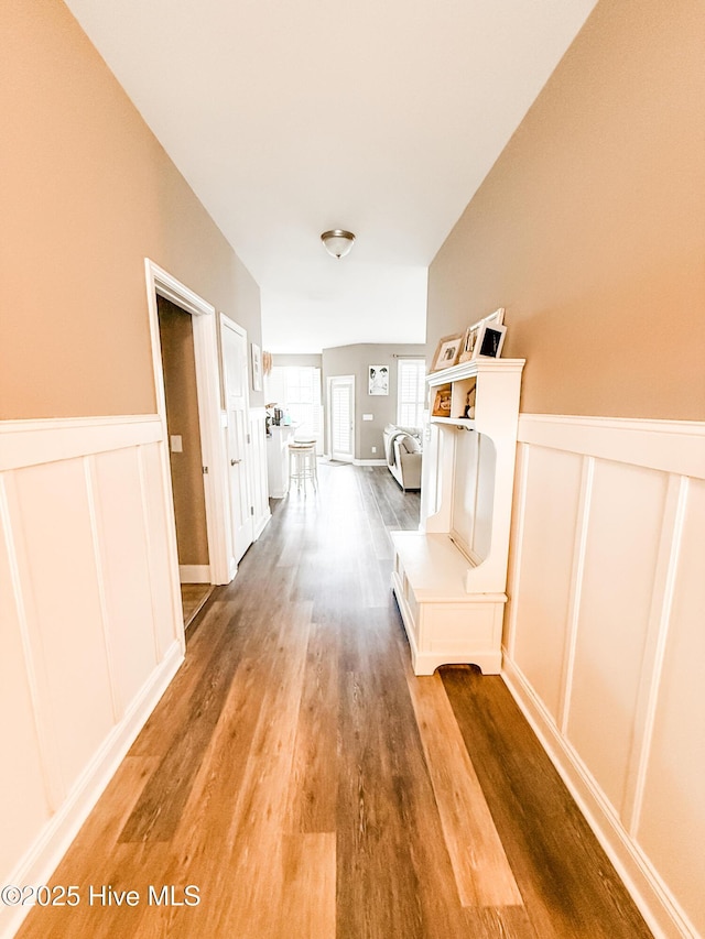 hallway with hardwood / wood-style flooring and vaulted ceiling