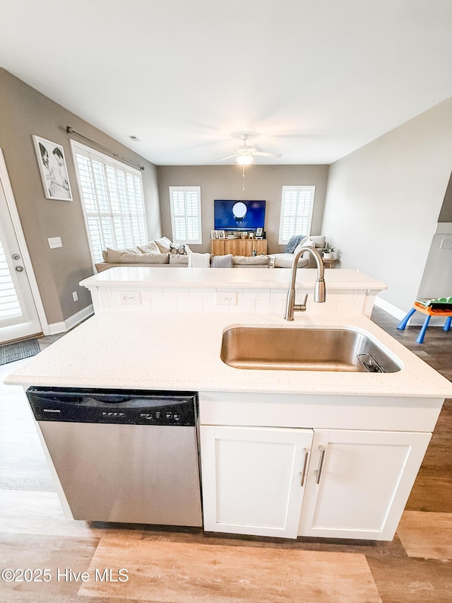 kitchen featuring dishwasher, sink, a center island with sink, and white cabinets