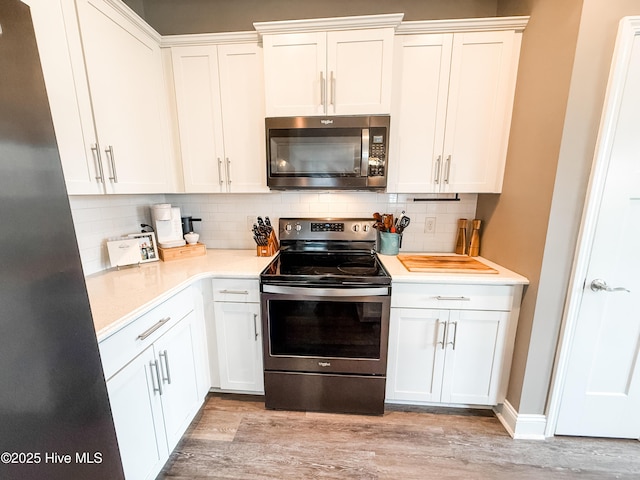 kitchen featuring white cabinetry, decorative backsplash, stainless steel appliances, and light wood-type flooring