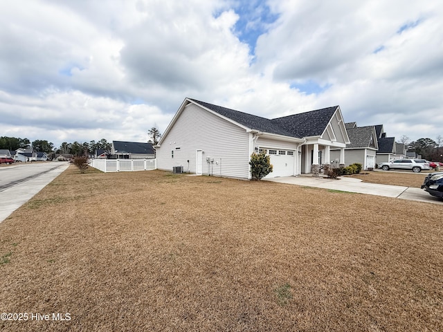 view of side of home featuring a garage, central AC, and a lawn