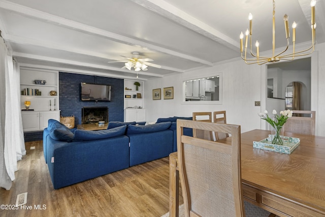 3401 Taylor St, Morehead City, NC 28557 - living room featuring hardwood / wood-style flooring, built in shelves, a brick fireplace, ceiling fan with notable chandelier, and beamed ceiling