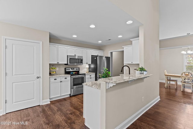 kitchen with light stone counters, dark wood-type flooring, white cabinets, and appliances with stainless steel finishes