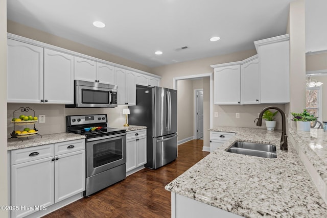 kitchen with sink, stainless steel appliances, light stone countertops, white cabinets, and dark hardwood / wood-style flooring