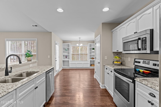 kitchen featuring dark wood-type flooring, sink, white cabinetry, pendant lighting, and stainless steel appliances