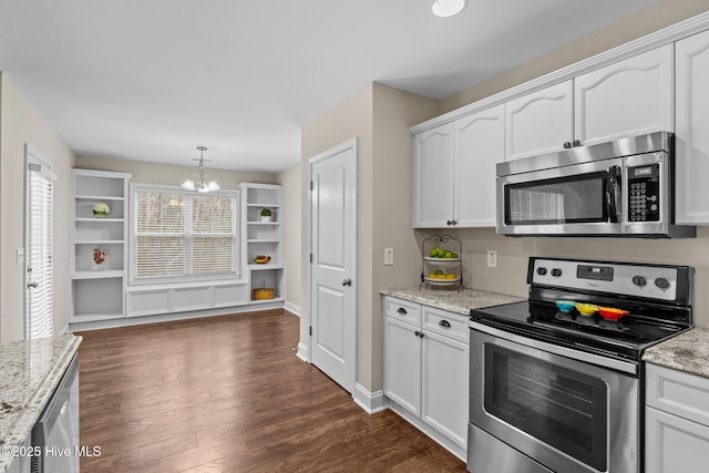 kitchen with hanging light fixtures, white cabinetry, appliances with stainless steel finishes, and light stone counters