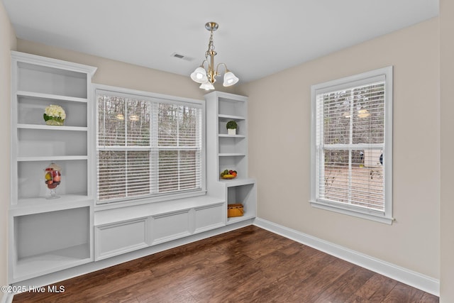 unfurnished dining area featuring an inviting chandelier and dark hardwood / wood-style flooring