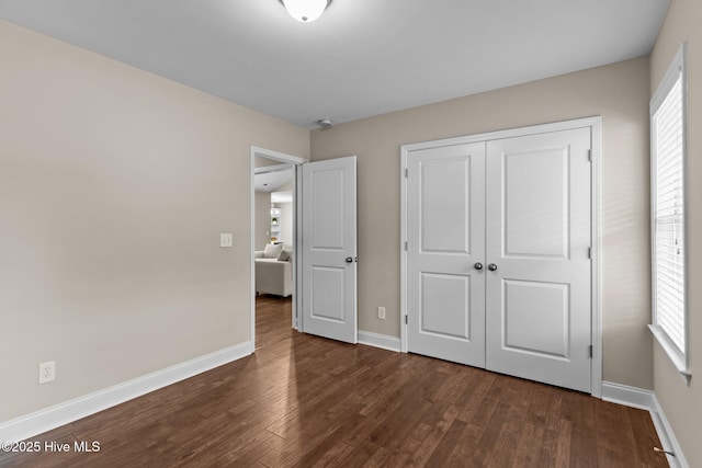 unfurnished bedroom with a closet and dark hardwood / wood-style floors