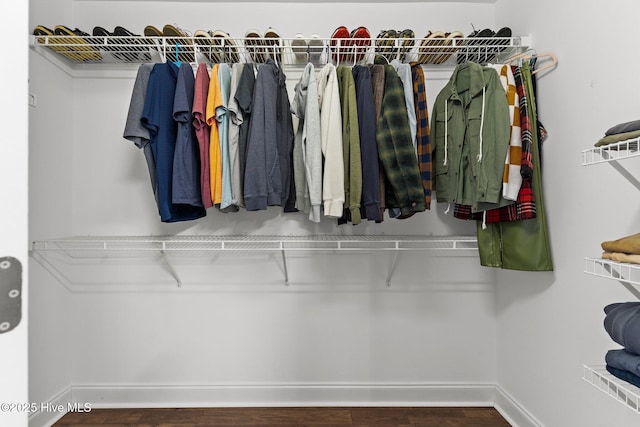 walk in closet with dark hardwood / wood-style floors