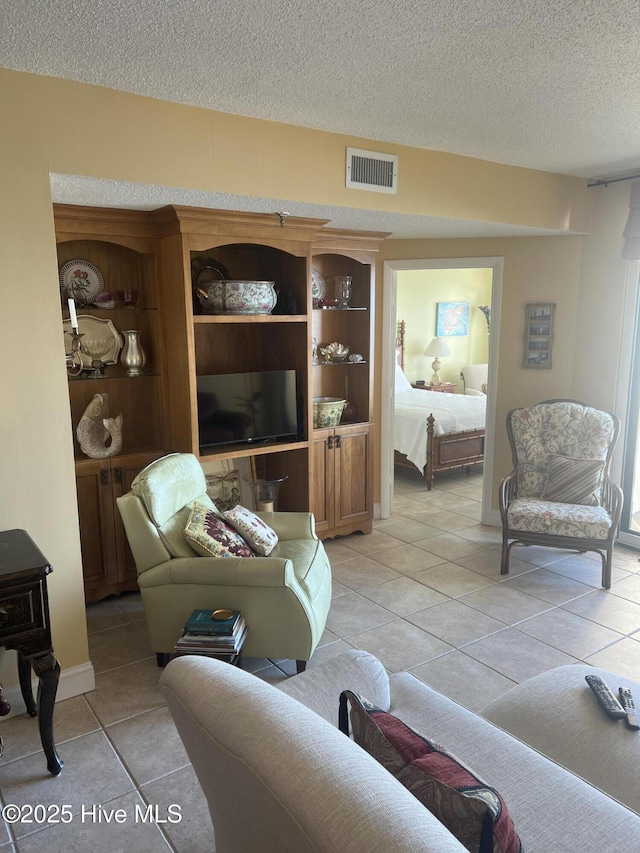 living room with light tile patterned floors, a textured ceiling, and visible vents