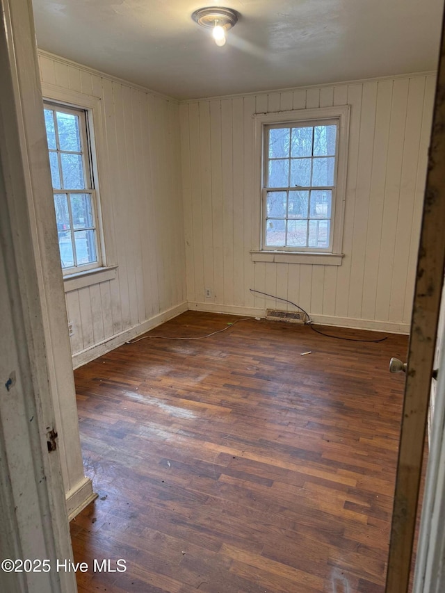 unfurnished room featuring dark wood-style floors, a healthy amount of sunlight, and baseboards