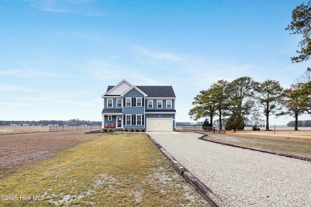 view of front of home with a garage, a front lawn, and a rural view