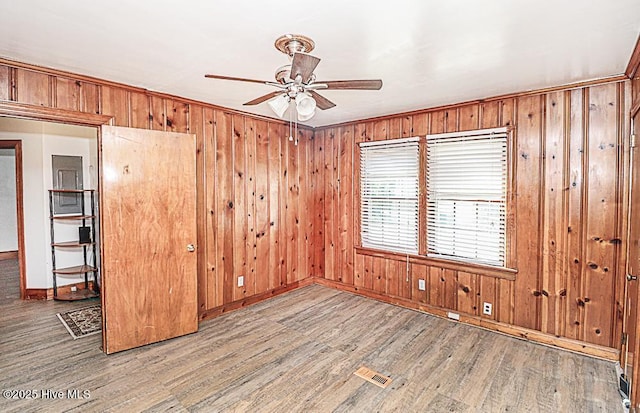 spare room featuring wooden walls, ceiling fan, and light wood-type flooring