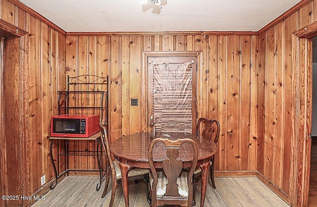 dining area featuring light hardwood / wood-style flooring and wooden walls