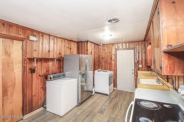 washroom with sink, light hardwood / wood-style flooring, and wood walls