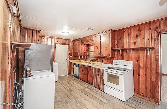 kitchen featuring stainless steel appliances, separate washer and dryer, wooden walls, and light wood-type flooring