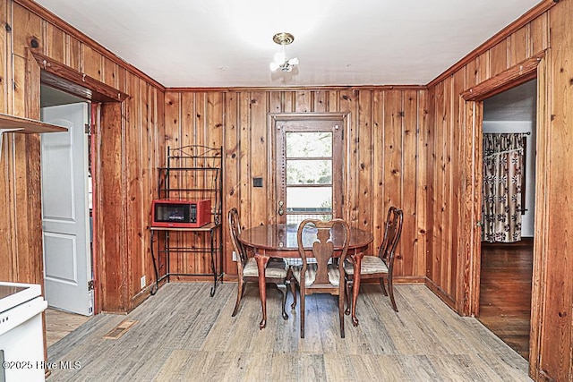 dining space with light hardwood / wood-style floors and wood walls