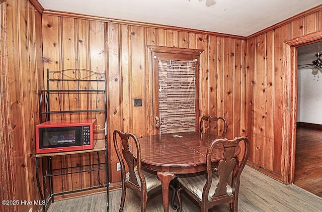 dining space featuring wood-type flooring and wood walls